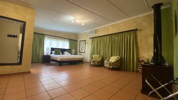 A hotel room with a bed, two armchairs, a desk with a computer, and a television.