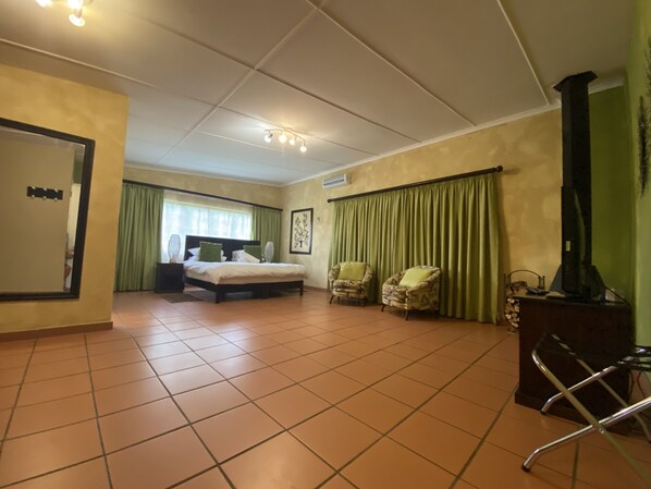 Una habitación de hotel con una cama, dos sillones, un escritorio con una computadora y un televisor.