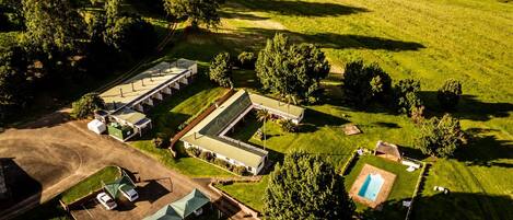 Vista aérea de una propiedad con varias construcciones, una piscina y campos verdes circundantes.