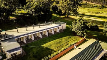 A modern building with a flat roof, multiple rooms with large windows, and a well-maintained lawn.