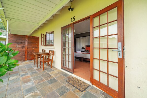 Una habitación con cama, escritorio y silla, con ventana y puerta.
