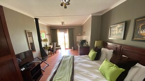A hotel room with a large bed, a television, a desk, and a chair. - St Ives Lodge (Lidgetton West)