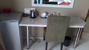 A compact kitchenette with a refrigerator, kettle, and a small countertop.