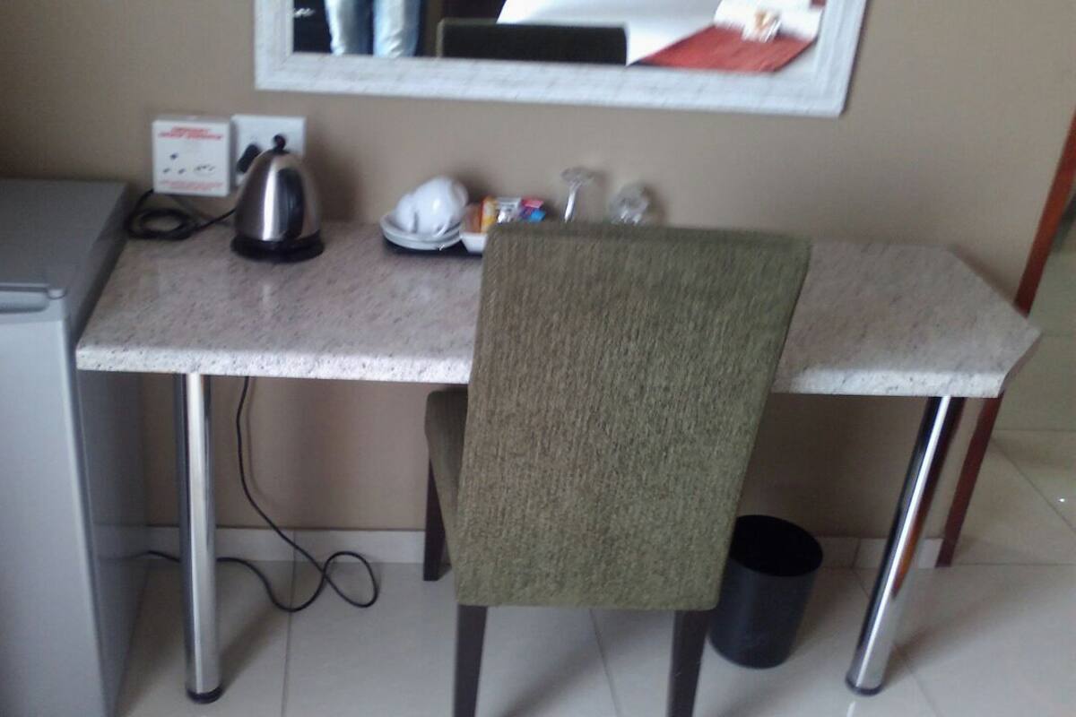 A compact kitchenette with a refrigerator, kettle, and a small countertop.