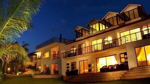 A multi-story hotel with balconies and large windows, surrounded by palm trees. - La Dolce Vita Guest House (Hartbeespoort)