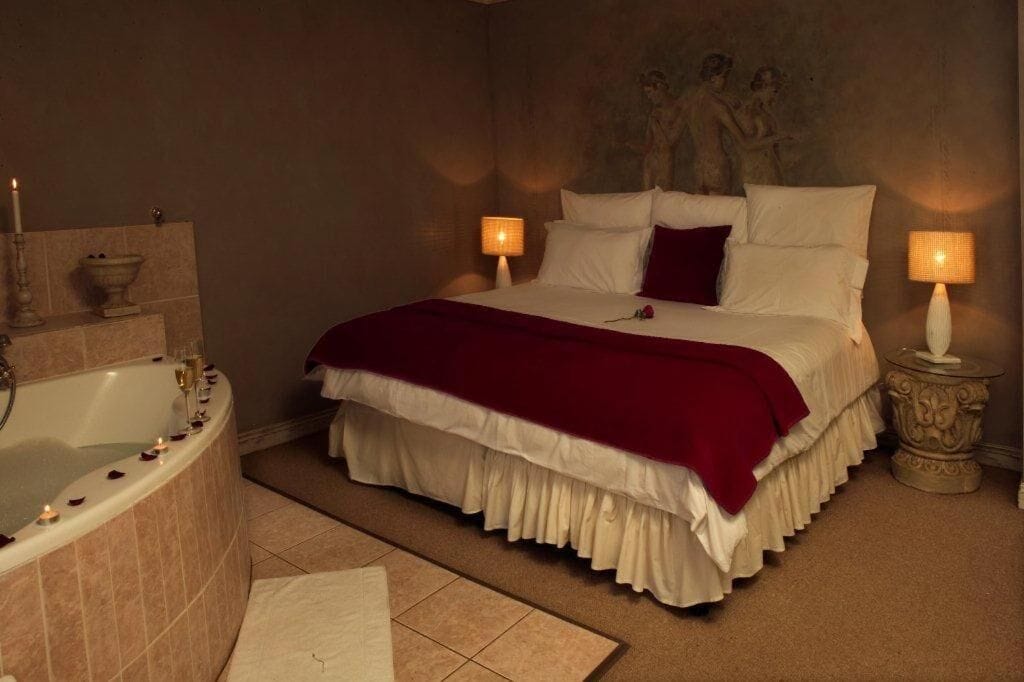 Ein Schlafzimmer mit einem großen Bett, einer Badewanne und zwei Nachttischlampen.