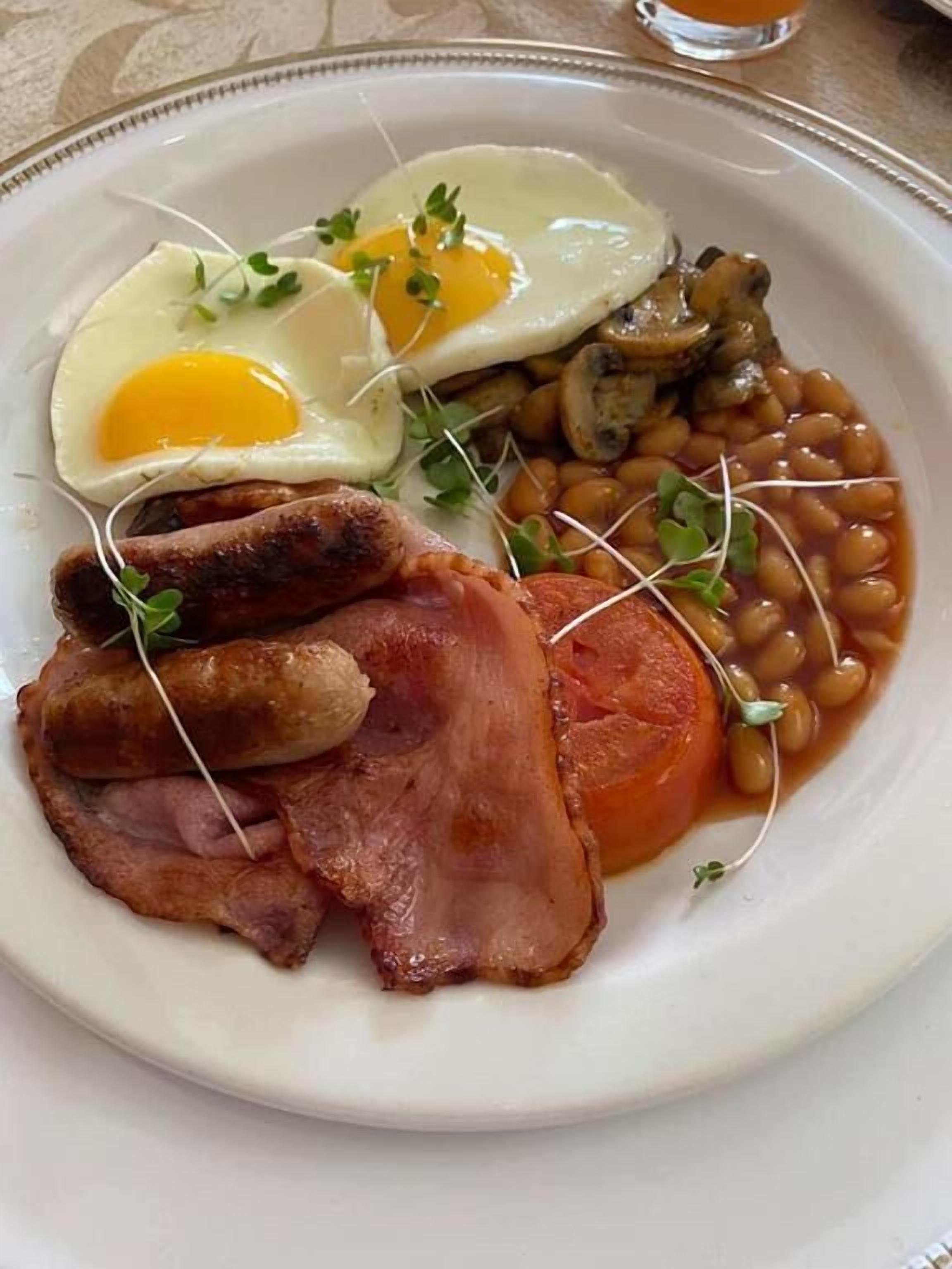 Un plato de comida con huevos, frijoles, tocino y champiñones.