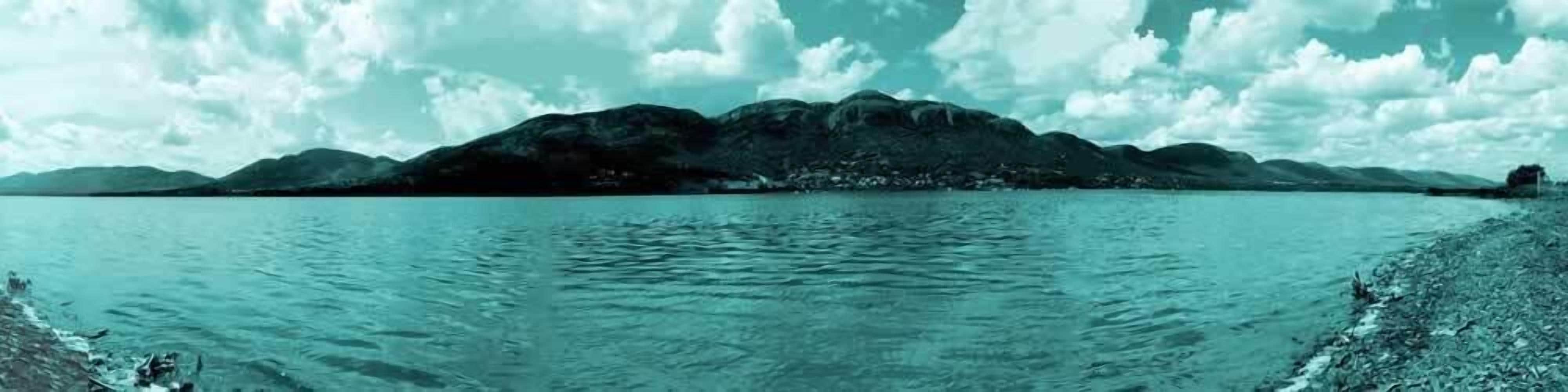 Een rustig meer met bergen op de achtergrond.