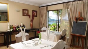A dining area with tables set for four, a wine rack, a chalkboard, and a view of the outdoors. - La Dolce Vita Guest House (Hartbeespoort)