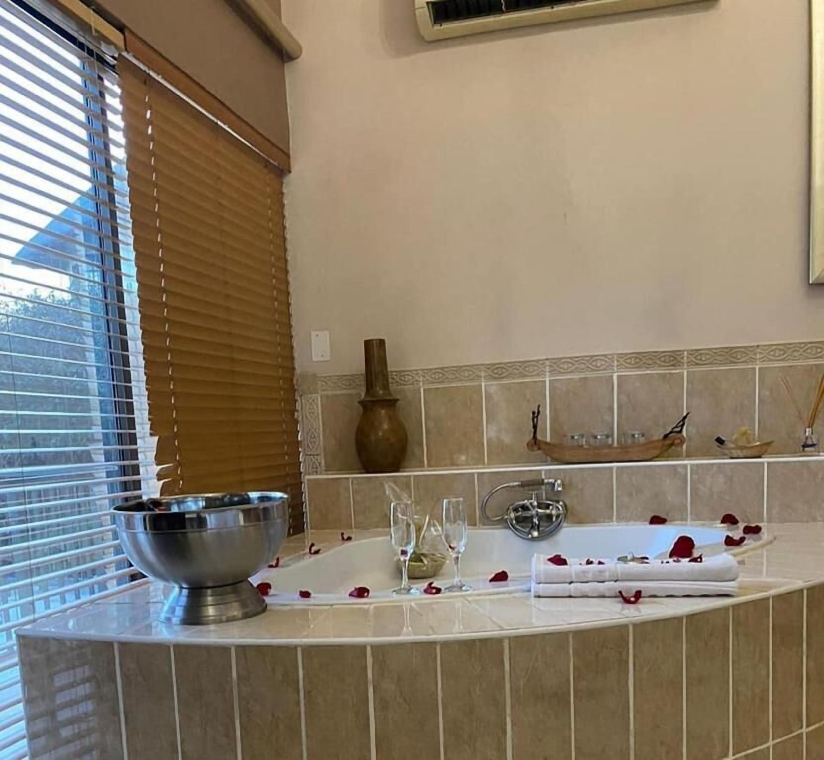 Un baño con una bañera, lavamanos, un florero y un perchero para toallas.