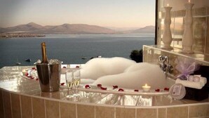 A luxurious bathroom with a bathtub, champagne, and rose petals. - La Dolce Vita Guest House (Hartbeespoort)
