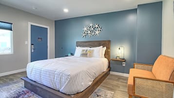 A bedroom with a bed, a chair, a nightstand, and a wall decoration.