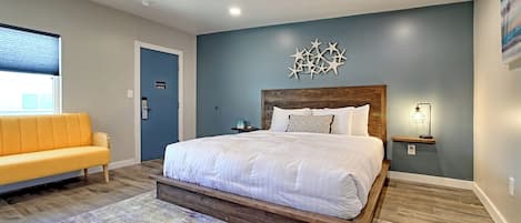 A bedroom with a bed, a nightstand, a wall-mounted lamp, and a window with blinds.