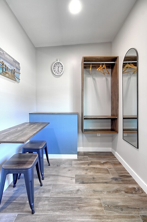 Una habitación con una pared azul decorativa, una mesa de madera con bancos, un reloj, un perchero y un espejo.