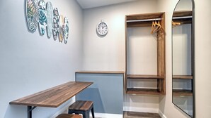 A room with a wooden table and bench, a clock on the wall, and a wooden closet with shelves. - White Caps Motel (Ventura)