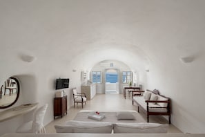 A spacious room with a large bed, a desk, and a view of the sea.
