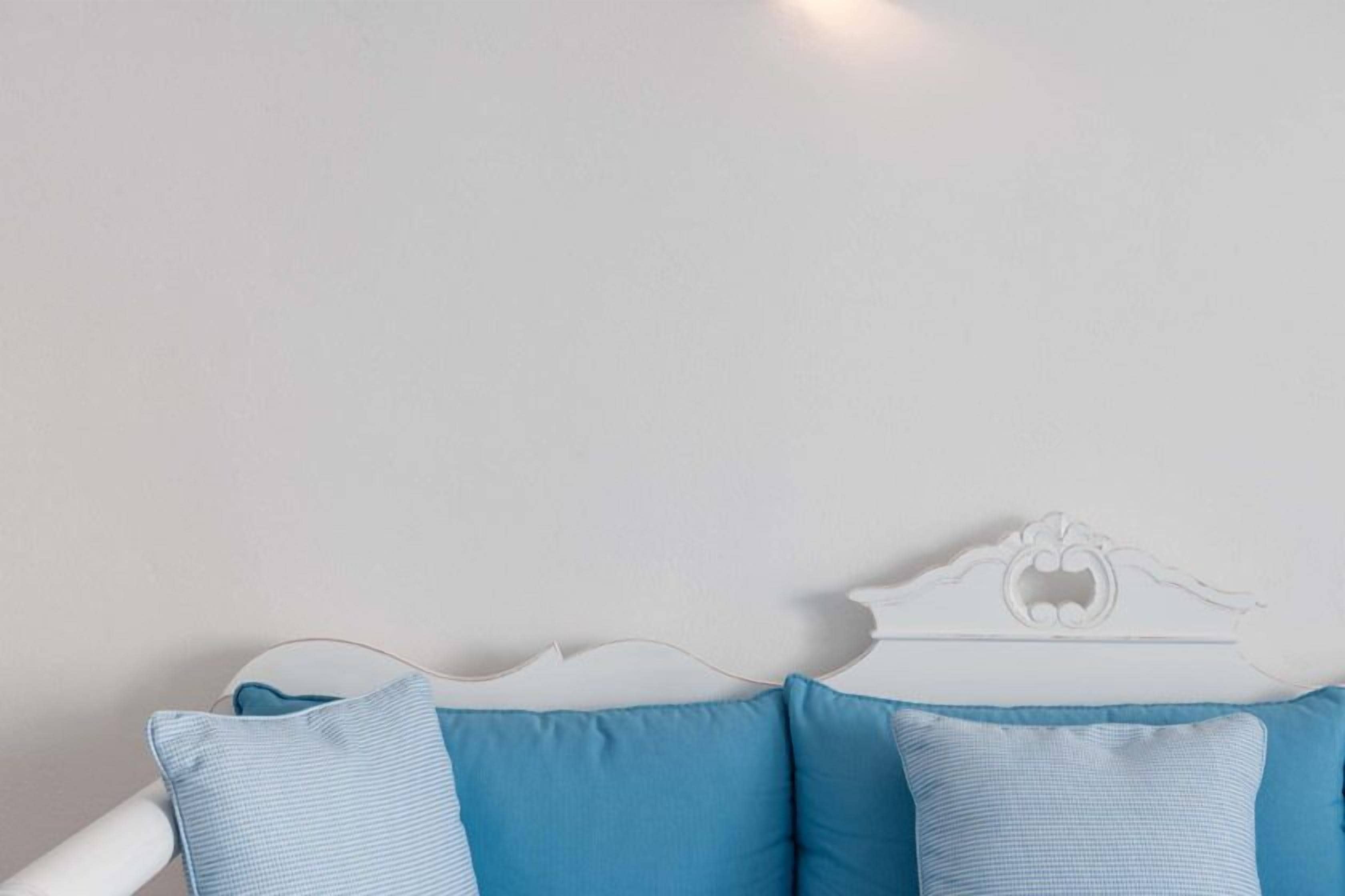 A bed with a white headboard and two blue pillows.