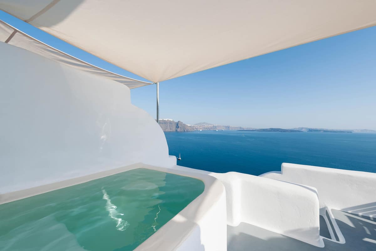 A white infinity pool with a clear view of the ocean and distant land.