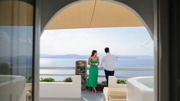 A couple on a balcony overlooking a scenic view of the sea and mountains.