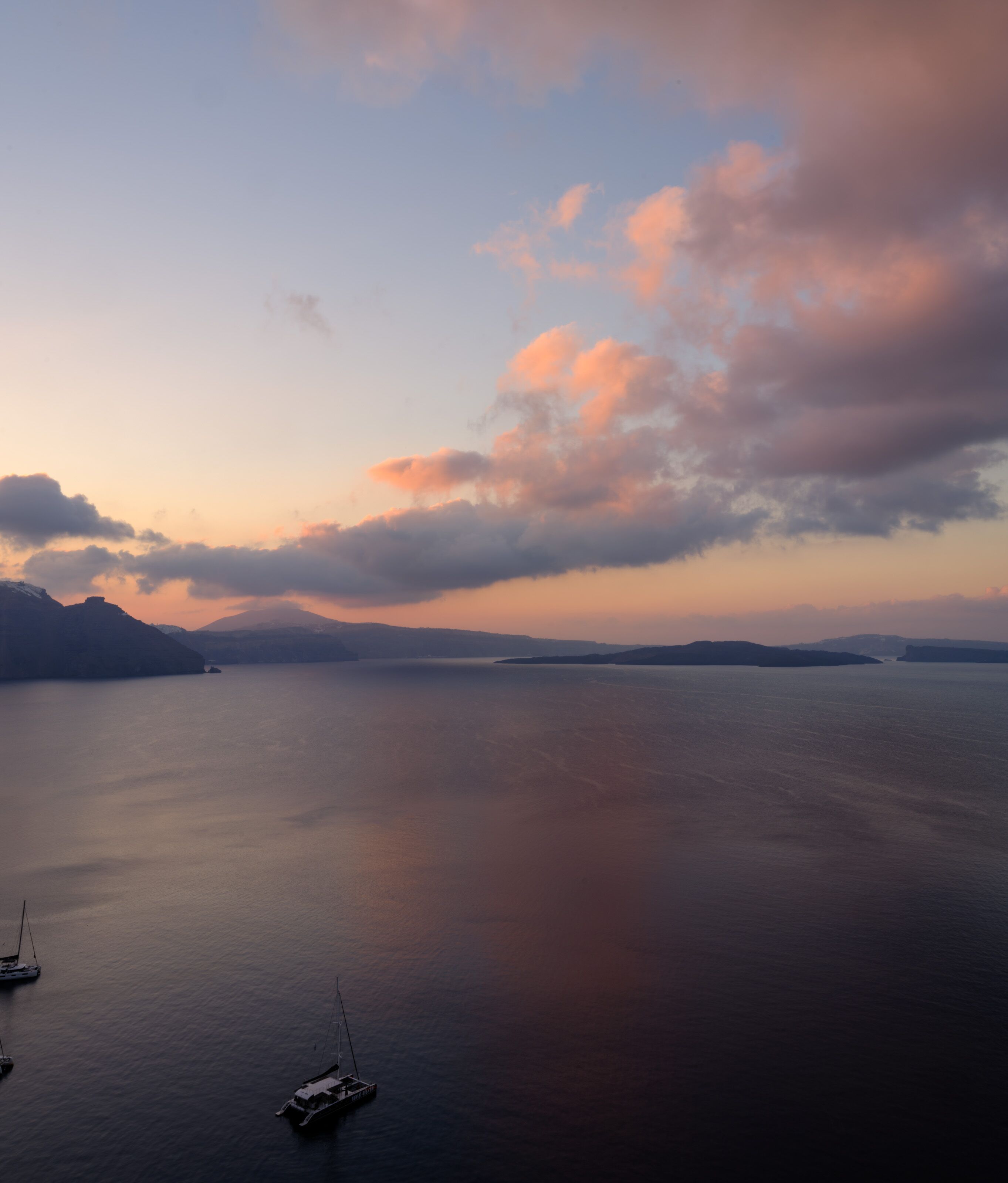 A calm body of water with boats, a clear sky, and distant landforms.