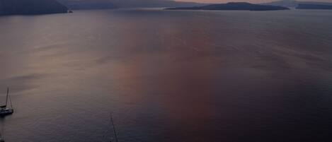 A calm body of water with boats, a clear sky, and distant landforms.