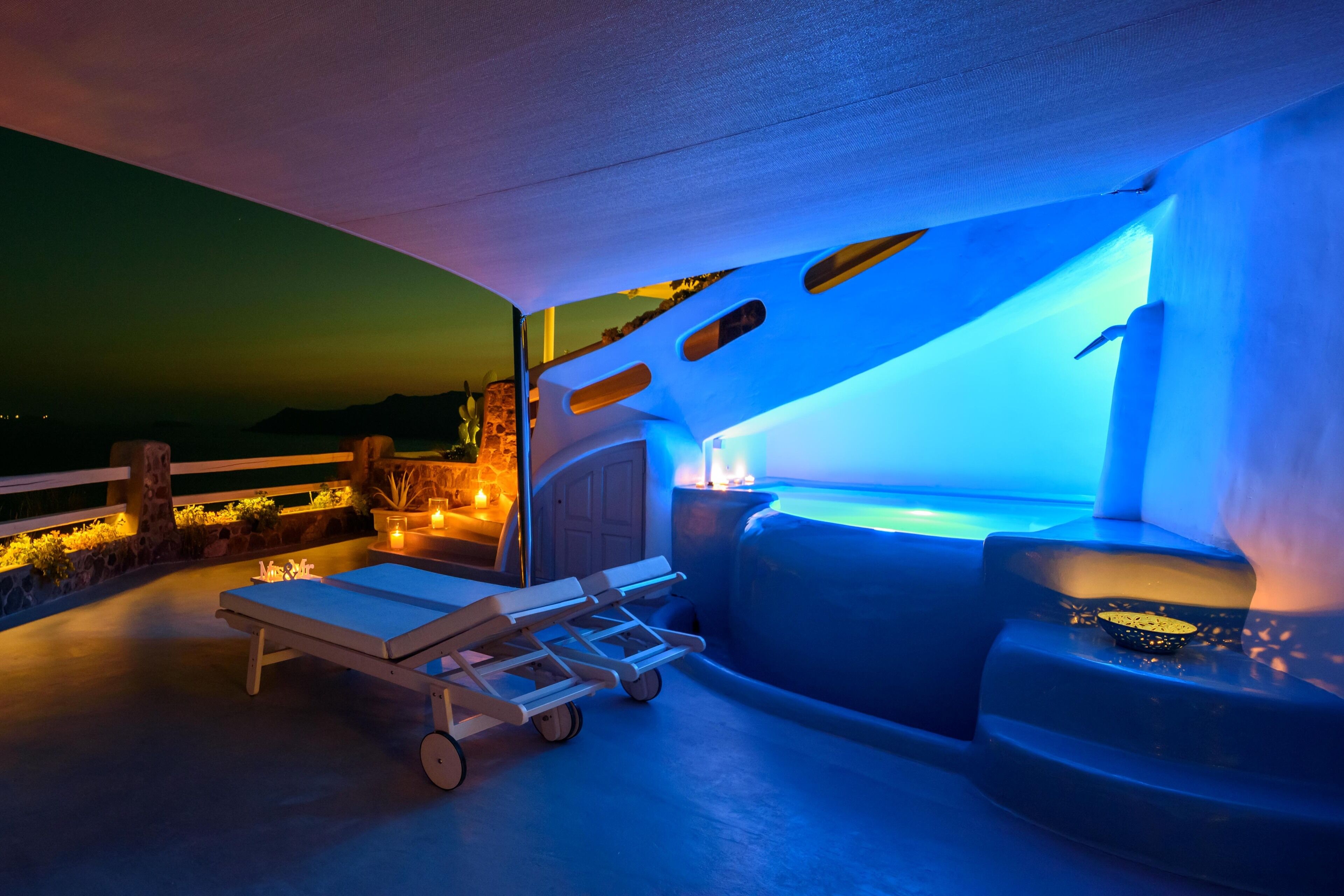 Un área de lounge en la azotea con piscina, sillones y una pequeña mesa.