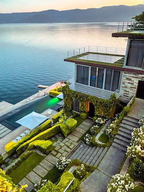 A modern building with a pool, surrounded by well-manicured gardens and a view of the water. - Cardedeu Residence (El Congo)