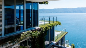 A modern building with large windows overlooking a body of water and distant hills.