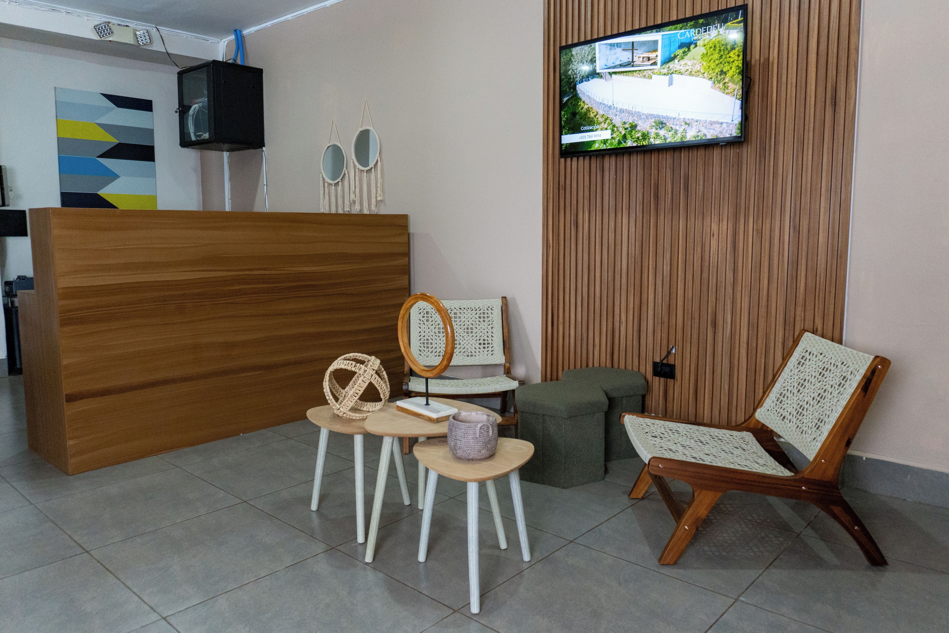 A reception area with a wooden reception desk, a television mounted on the wall, and a seating area with wicker chairs and a cushioned bench.