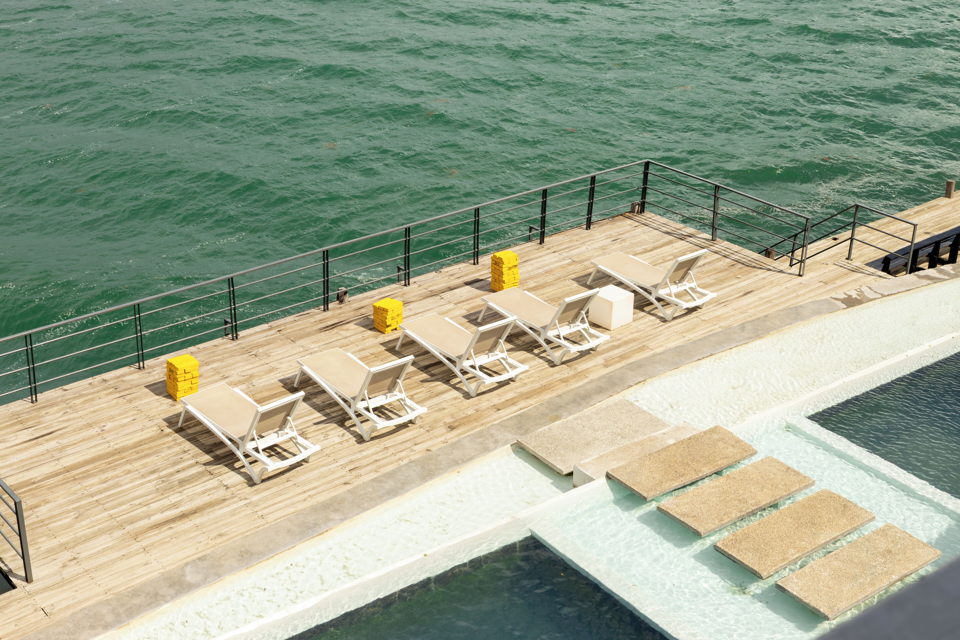 A wooden deck with lounge chairs and a pool.