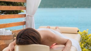 A person receiving a massage in a room with a view of a lake.