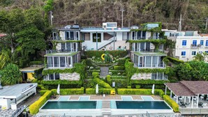 A modern hotel with multiple levels, a central pool, and lush landscaping.