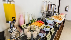 A buffet with various food items and beverages, including a yellow drink dispenser, cheese and crackers, and different types of dips. - Tambo Dos de Mayo (Lima)