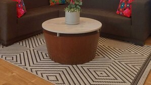 A modern living room with a round coffee table, two sofas, a decorative wall hanging, and a large window with curtains. - Tambo Dos de Mayo (Lima)