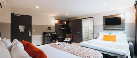 Habitación de hotel con dos camas, un escritorio, un televisor y un baño.
