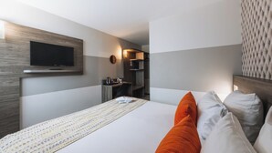 A hotel room with a bed, a flat-screen TV mounted on the wall, a desk with a chair, and a microwave. - Best Western Portes d’Aquitaine Agen Sud (Le Passage)