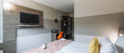 Una habitación de hotel con cama, escritorio, silla, televisor y armario.