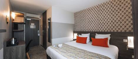 A hotel room with a bed, a desk, and a chair.