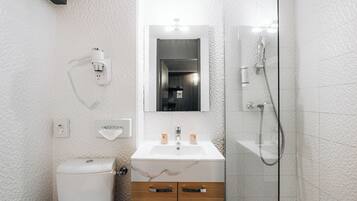 Un baño moderno con inodoro, lavamanos, espejo y ducha.