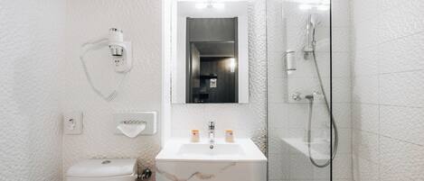 Un baño moderno con inodoro, lavamanos, espejo y ducha.