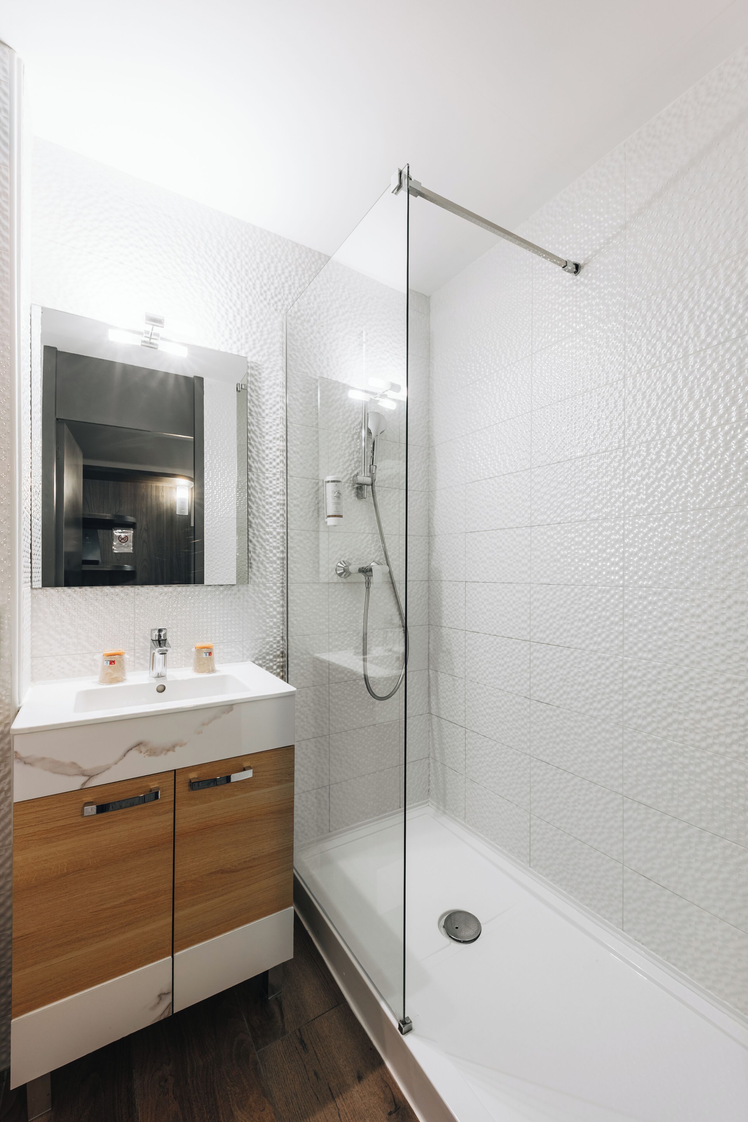 Un baño moderno con ducha de vidrio, lavamanos de mármol y muebles de madera.