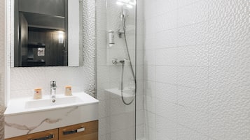 Ein modernes Badezimmer mit einer gläsernen Dusche, einem Marmorwaschbecken und Holzschränken.