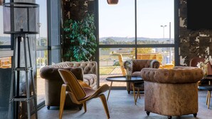Een modern interieur met een groot raam, leren banken, een klein tafeltje en een potplant.