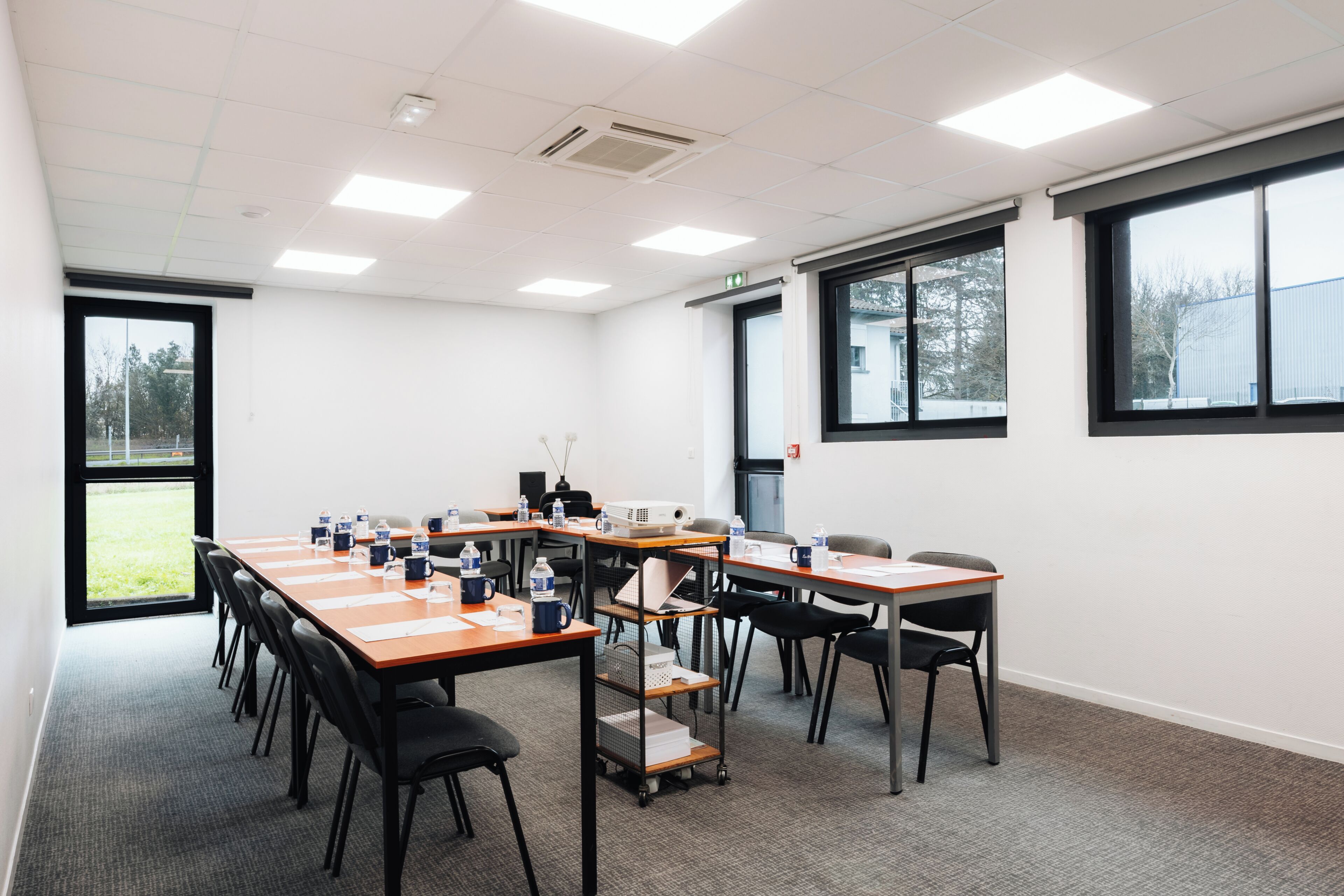 A conference room with a long table, chairs, a projector, and a water dispenser.