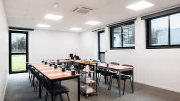A conference room with a long table, chairs, a projector, and a water dispenser.