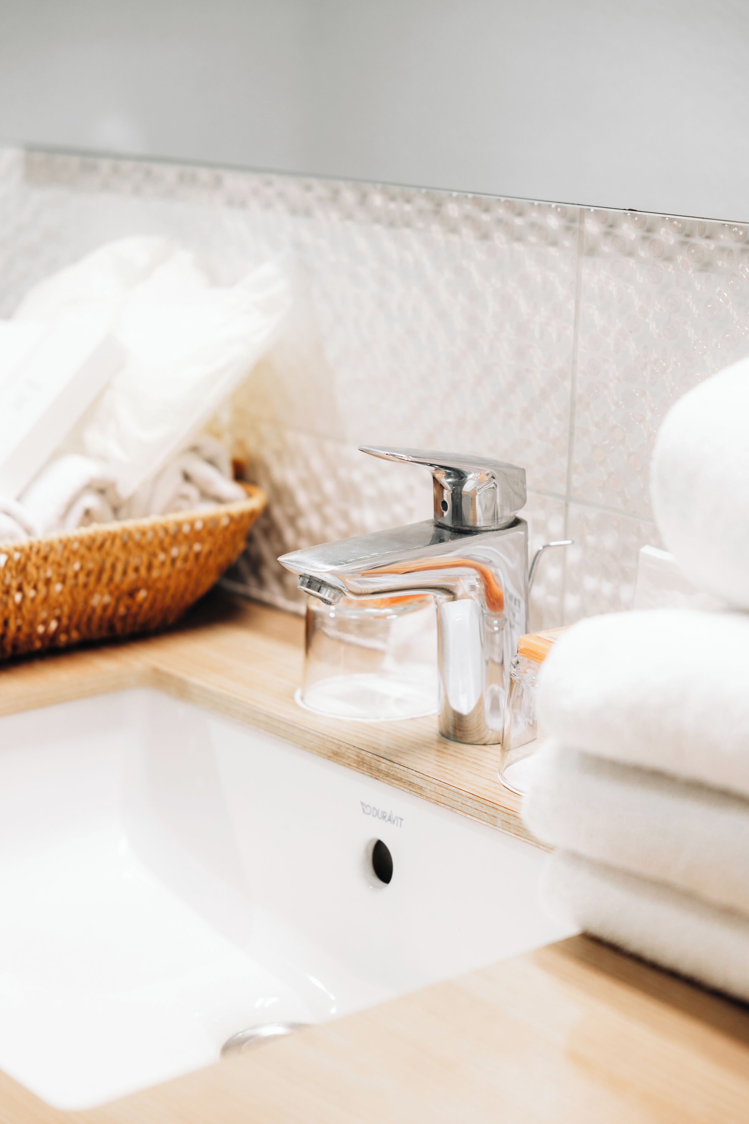 Un lavabo con rubinetto cromato, un portasapone in vetro e un asciugamano bianco.