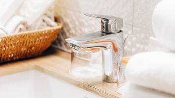Un lavabo de baño con grifo cromado, un jabonero de vidrio y una toalla blanca.