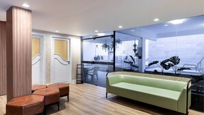 A modern interior with a green sofa, wooden flooring, and glass doors leading to an outdoor area with plants. - H Hotel (Balneário Camboriú)