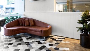 A modern interior with a curved leather sofa, a hexagonal patterned floor, and a potted plant. - H Hotel (Balneário Camboriú)