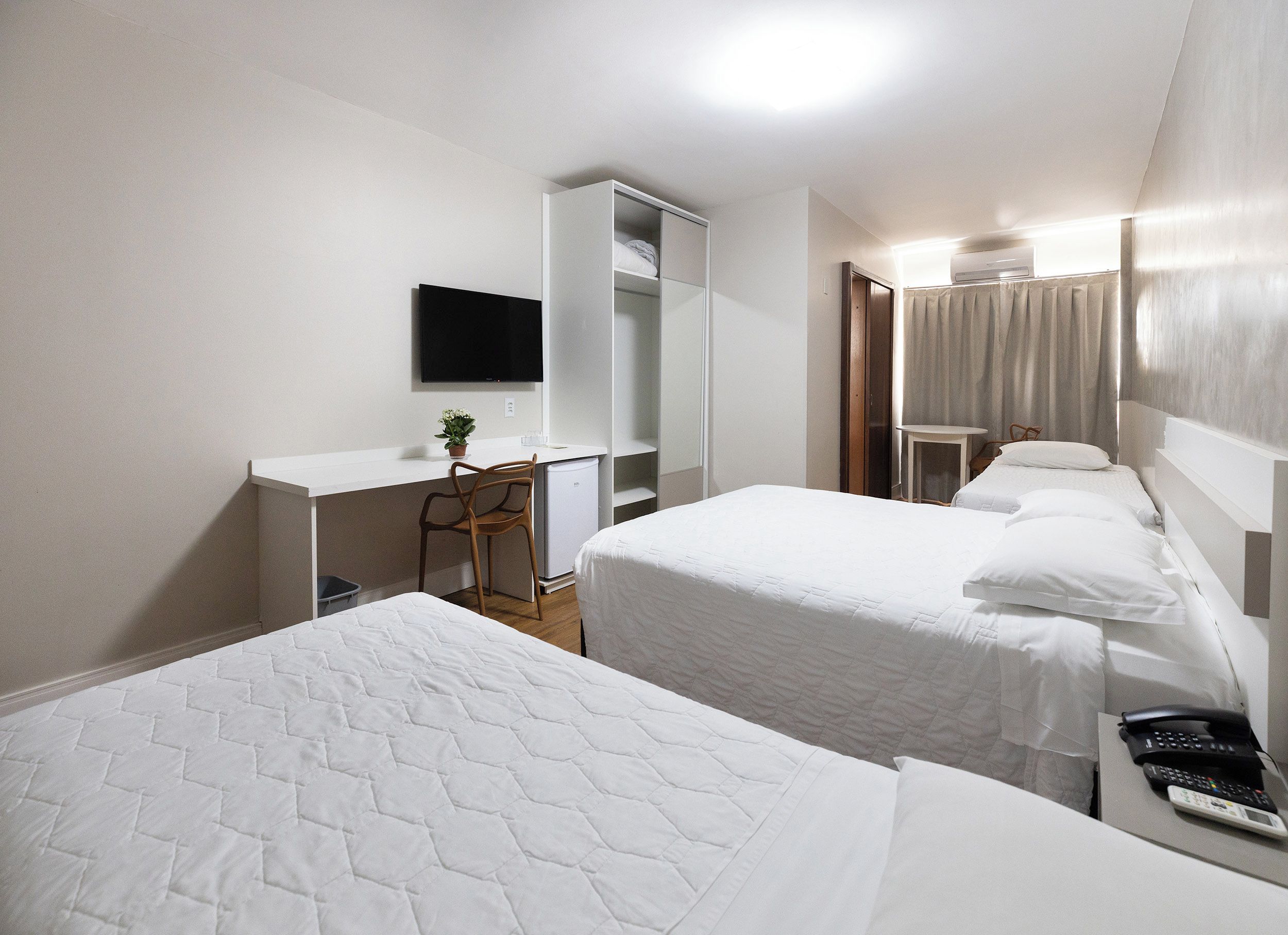 A hotel room with two beds, a desk, a television, and a wardrobe.
